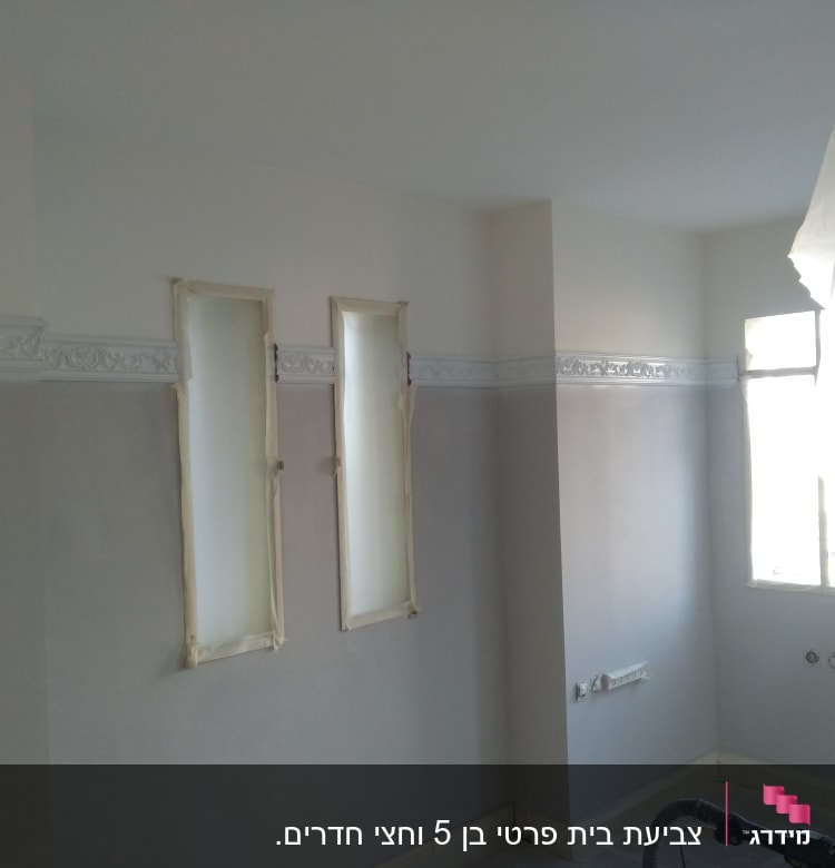 קירות צבועים בשני גוונים עם מסגרות חלונות מכוסות